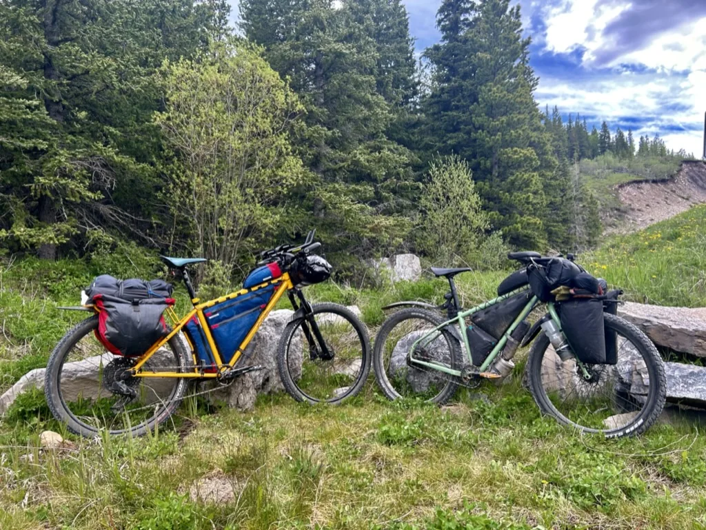 Two fully loaded bikepacking bikes beside a rocky foothills trail