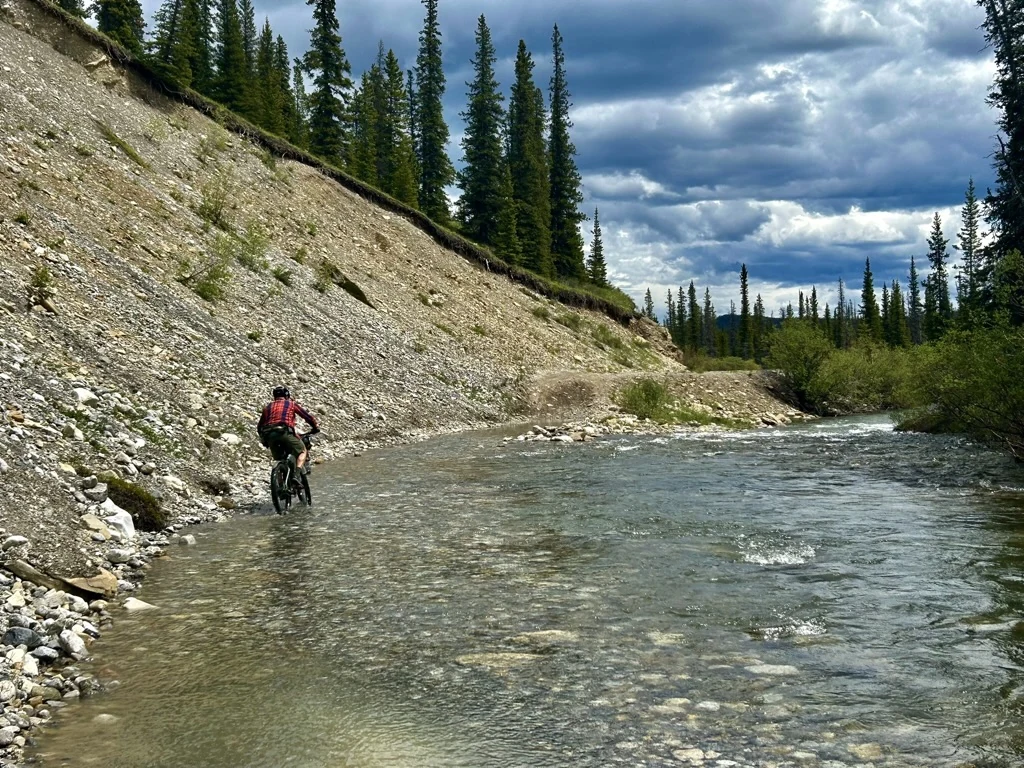 Bikepacker riding through a river crossing on the Cardinal Divide route