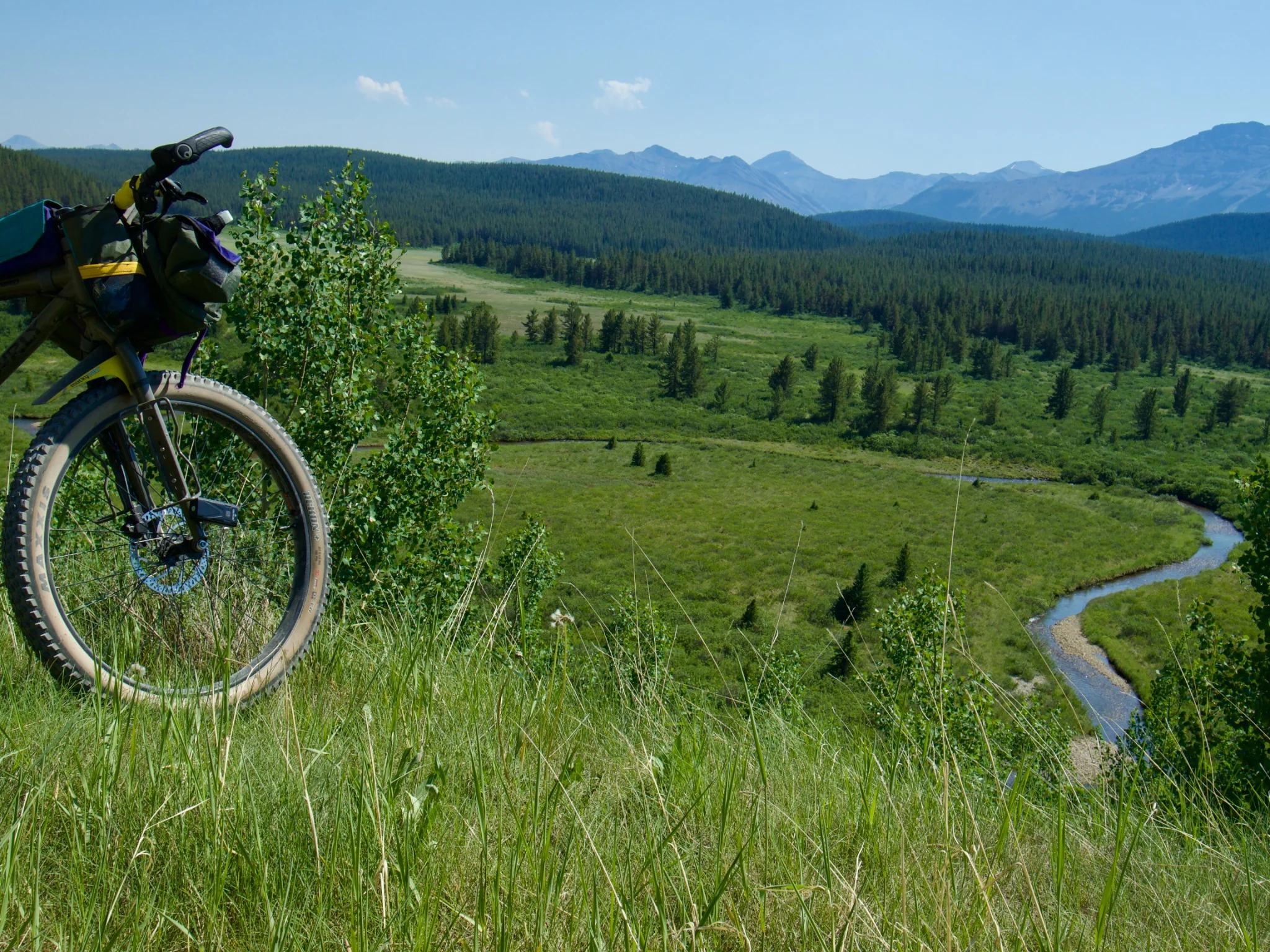 Loaded bike overlooking a broad forested valley and Alberta mountain range
